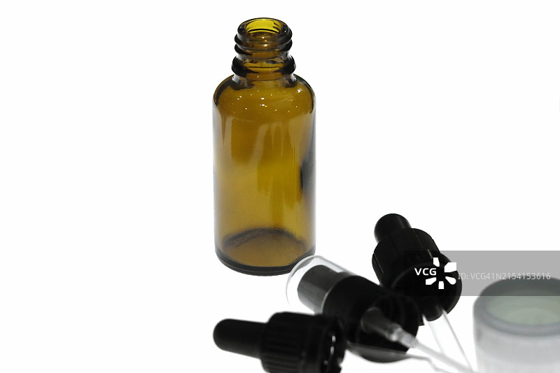 用于盛放化学液体、香水、精油和精华液的玻璃滴管容器，位于白色矩形台上图片素材
