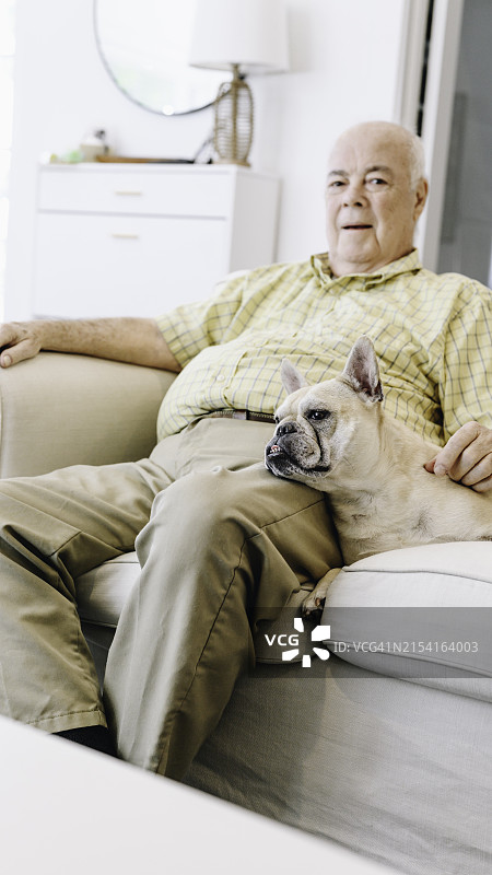 年长的拉丁裔男人和他的巴哥犬在家放松图片素材