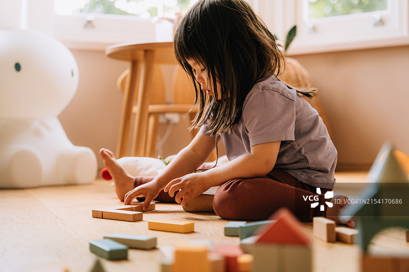 在卧室里玩积木的亚洲幼儿女孩图片素材