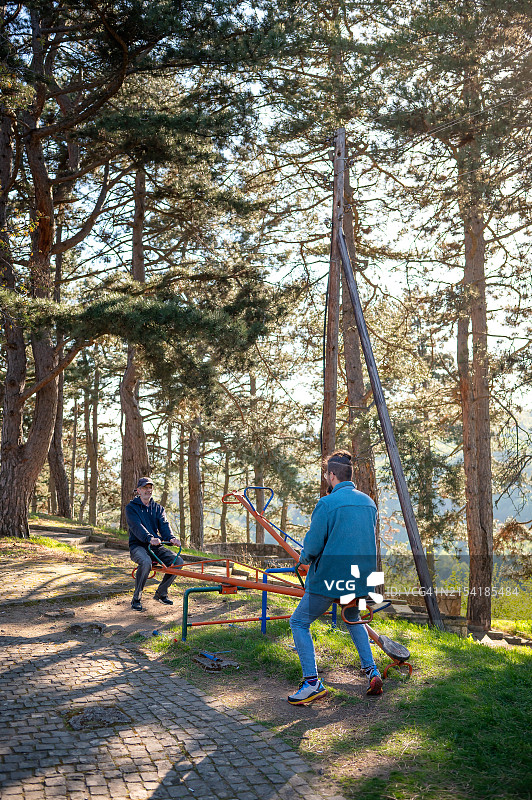 父子在公园里玩跷跷板图片素材