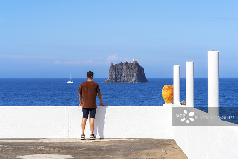 男人在露台上欣赏斯特龙博利基奥岛的景色，伊奥利亚群岛，意大利图片素材