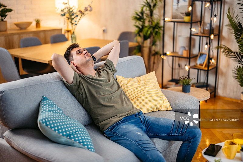 在舒适的沙发上休息的放松的年轻男人图片素材