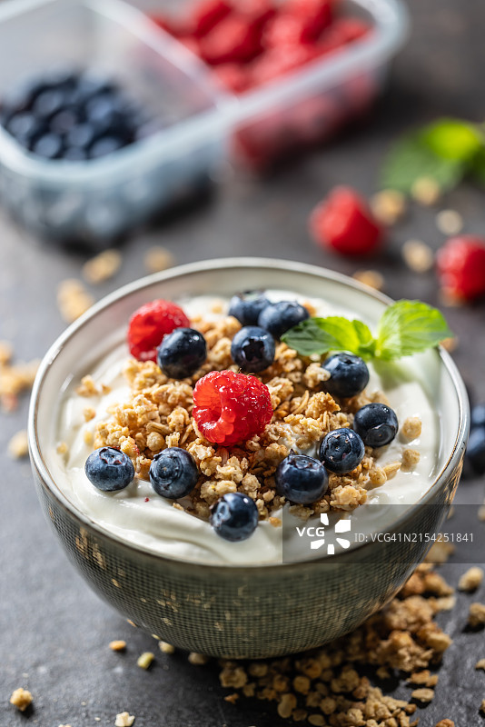 含有麦片、覆盆子和蓝莓的酸奶碗：富含蛋白质、纤维和钙的健康早餐或零食，健康饮食和生活方式理念图片素材