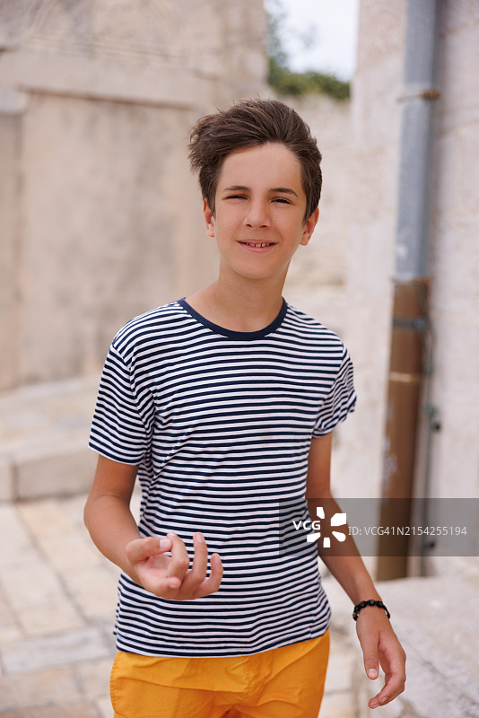 在海边小镇享受夏日的可爱少年，走在巷子里图片素材