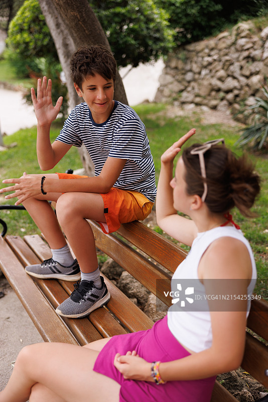在海边公园长椅上与兄弟击掌的少女图片素材