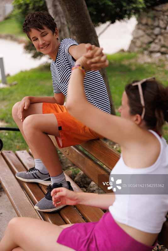 少年和妹妹在公园长椅上掰手腕图片素材