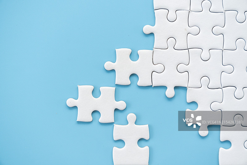 蓝色背景上的白色拼图图片素材