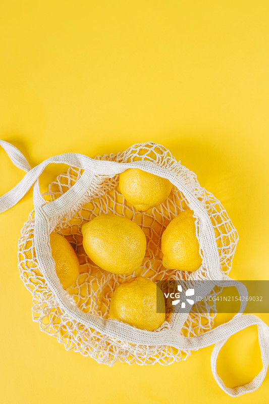 黄色背景上可重复使用的购物袋中新鲜柠檬的特写图片素材