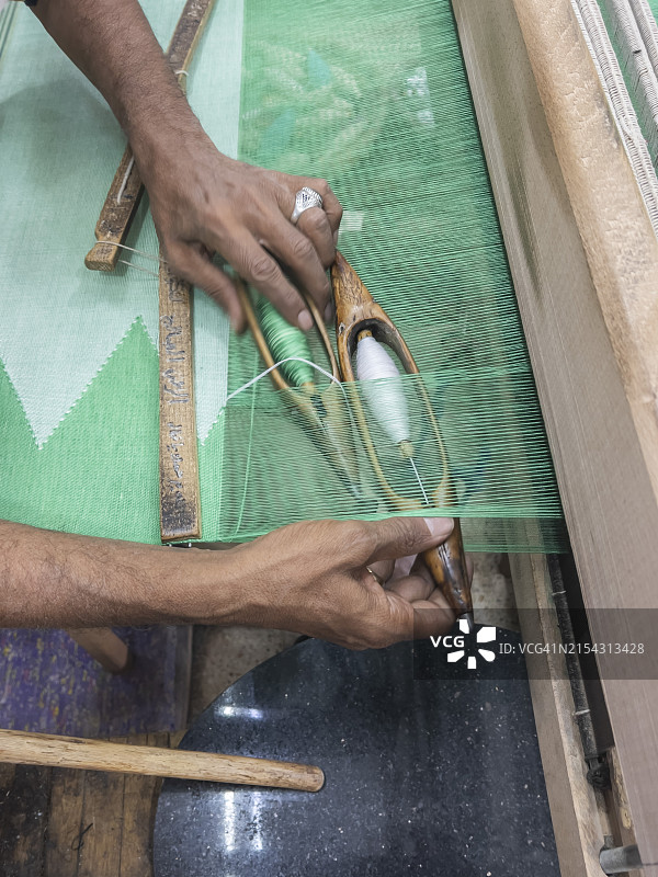 埃及男子在阿斯旺未完成的方尖碑商店里的织布机上工作图片素材