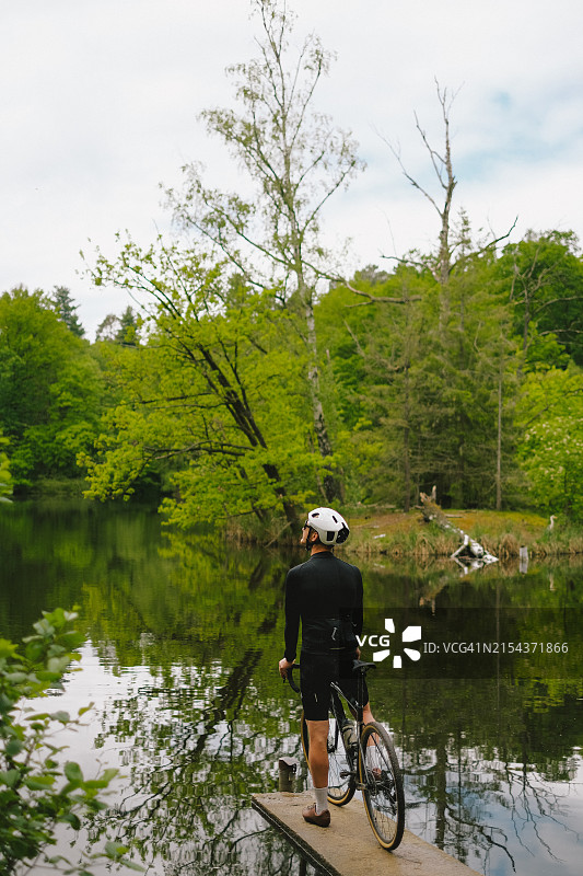 在湖边码头上骑行的公路自行车手图片素材