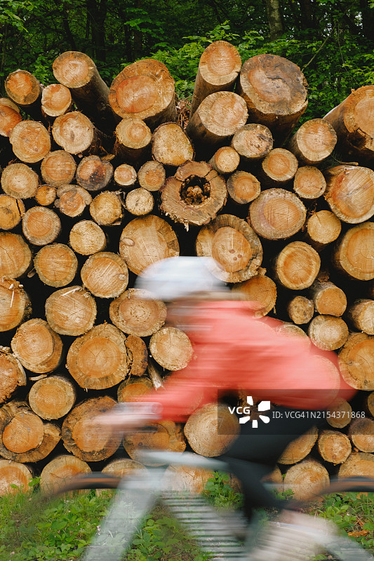 公路自行车手骑过堆叠的木头图片素材