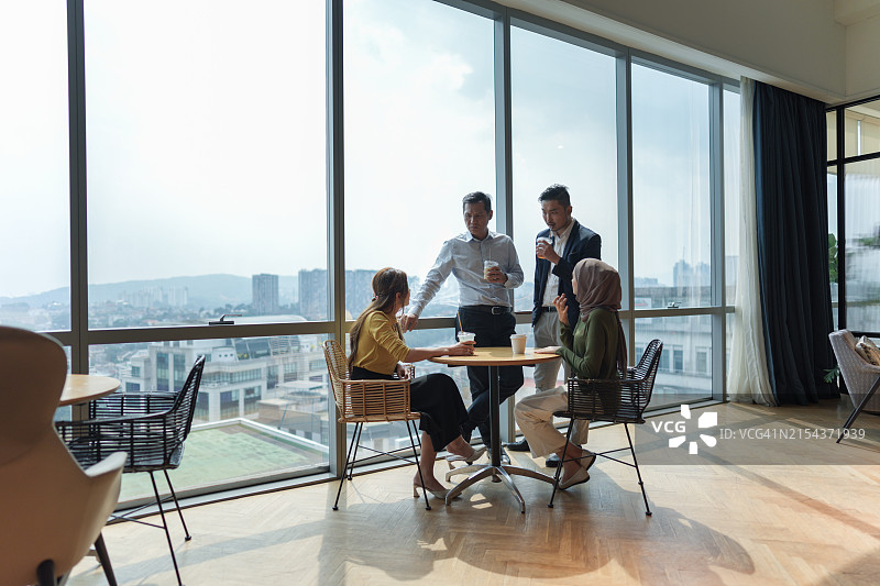 一群多元化的同事在现代办公室咖啡馆一边喝咖啡一边进行休闲谈话图片素材