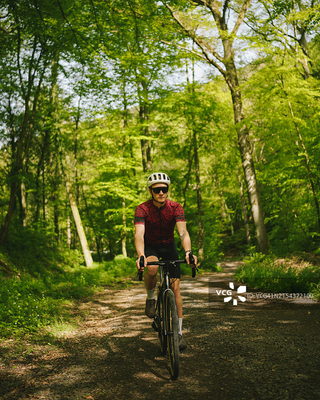 公路自行车骑行者穿过茂密的森林图片素材