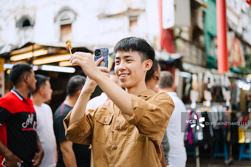 年轻的亚洲男人在吉隆坡唐人街拍摄街头美食照片图片素材