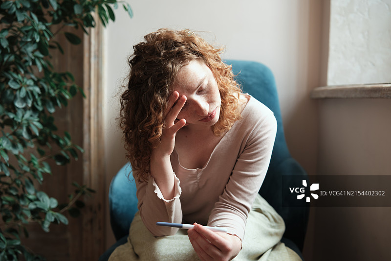 焦虑的年轻女子拿着验孕棒，在家中检测。涉及Z世代和堕胎议题图片素材