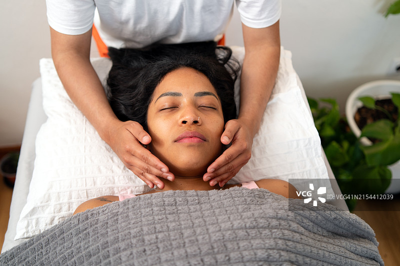 灵气治疗师轻轻地将手放在放松的西班牙裔患者头部附近图片素材