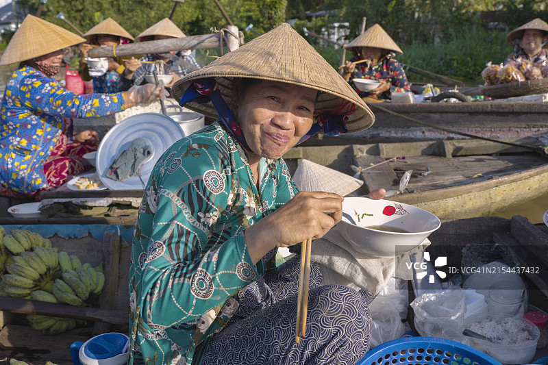 越南湄公河三角洲水上市场，越南妇女在吃著名的米粉汤图片素材