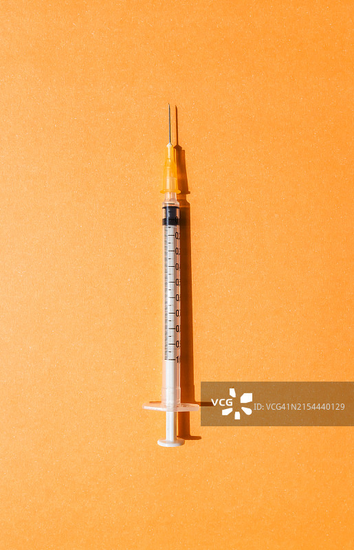 橙色背景上的注射器图片素材