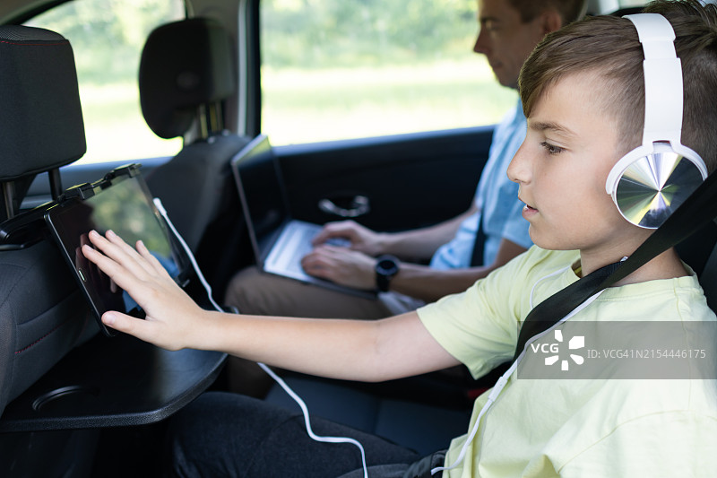 父子在汽车后座使用平板电脑和笔记本电脑旅行图片素材