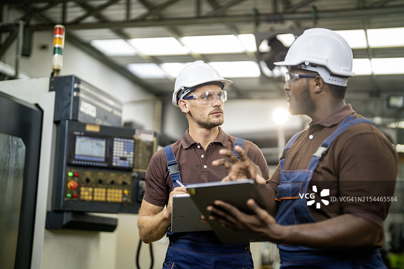 两名工程师在现代化工厂交谈，检查生产线机器并进行设置图片素材