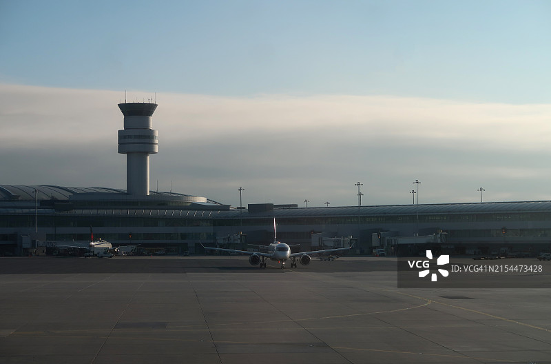 停机坪上双引擎飞机与机场空管塔台图片素材