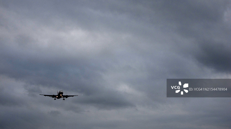阴天背景下准备降落的双引擎飞机图片素材