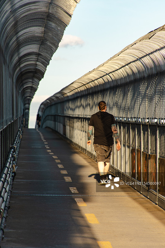 男人在蒙特利尔雅克·卡地亚大桥上行走背影图片素材