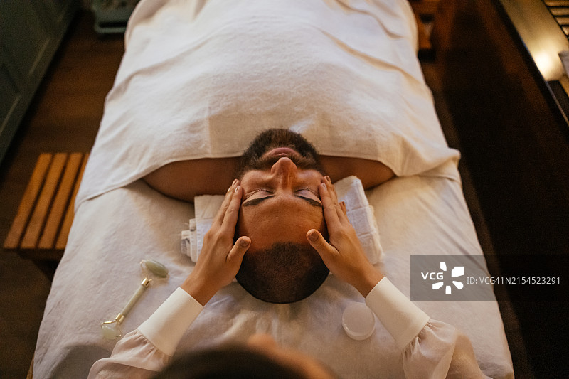 在水疗中心接受面部按摩的男人图片素材