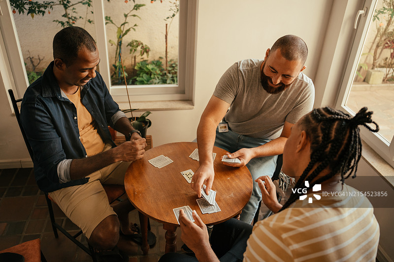 三个朋友玩纸牌游戏图片素材