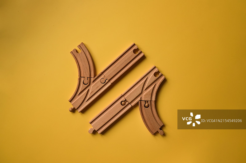 决策十字路口：黄色背景上的木制火车轨道交叉口，描绘了方向选择的概念图片素材