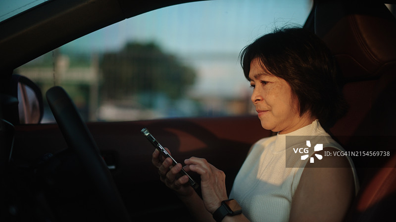 女人在停车场里在车里使用智能手机图片素材