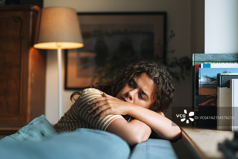 在家中房间沙发上坐着的卷发沮丧女性图片素材