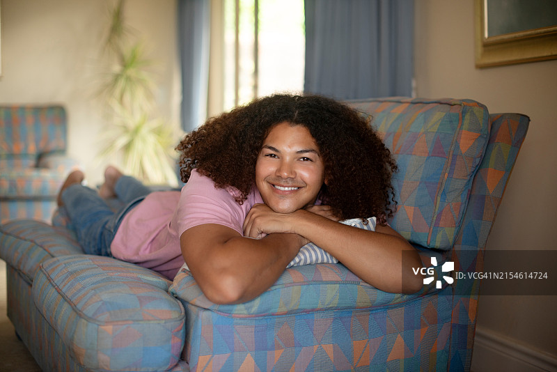 快乐放松：客厅里，男人在沙发上休息，态度积极自信图片素材