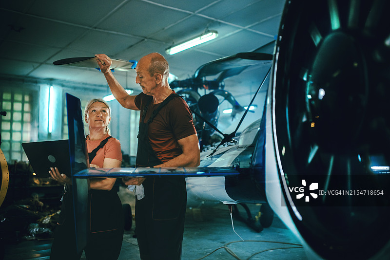 男女机械工程师在机库修理直升机图片素材