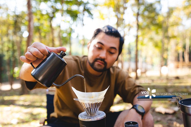 亚裔男子在清晨露营时煮咖啡图片素材