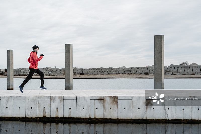 年长的男人在户外运动，在冬日里湖边跑步图片素材
