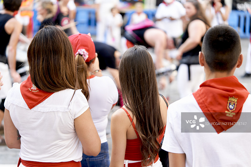 一群人穿着圣费尔明节日的服装站在潘普洛纳的街道上，后视图图片素材