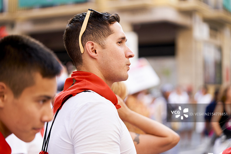 在西班牙潘普洛纳圣费尔明节期间，年轻男人专注地观看传统游行图片素材