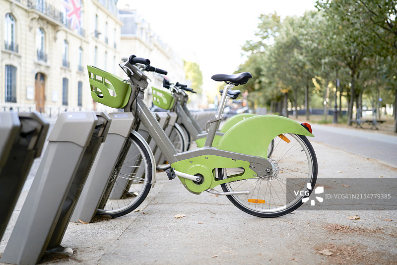 巴黎的自行车停车点，带绿色车筐，侧面角度，背景有树木图片素材