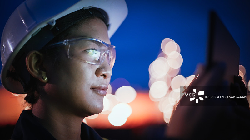 在夜间石油工厂和天然气炼油厂使用笔记本电脑的亚洲女工程师图片素材