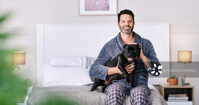 快乐，在卧室里，早上男人和狗在一起，用爱来照顾和支持。周末在家里与动物玩耍，放松身心，或者通过寄养小狗和宠物保险来保障安全图片素材