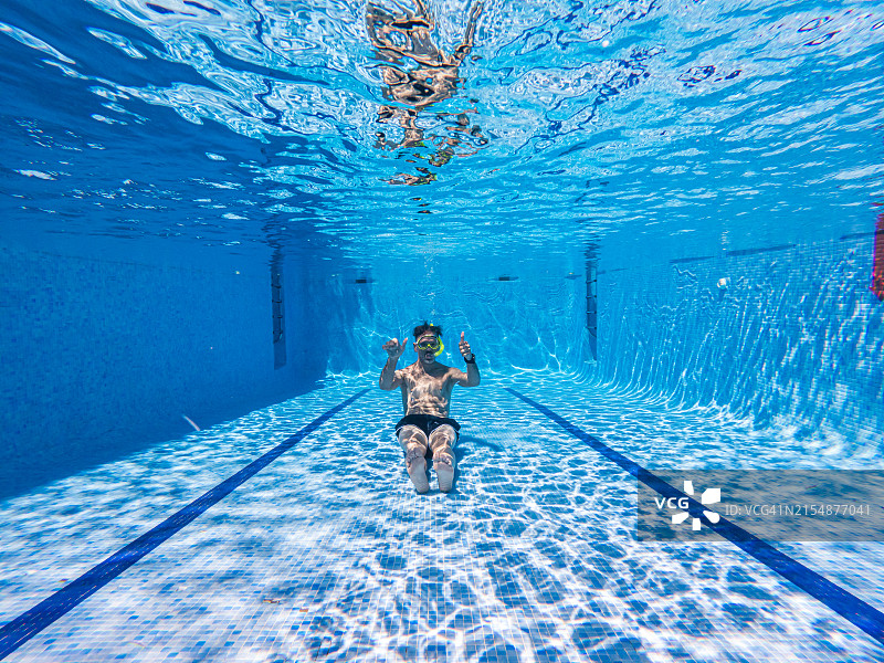 男人戴着护目镜和呼吸管在泳池底部，坐着并竖起大拇指，潜水员，泳池，呼吸管，OK手势，蓝色瓷砖，清水，游泳，沉浸，娱乐图片素材