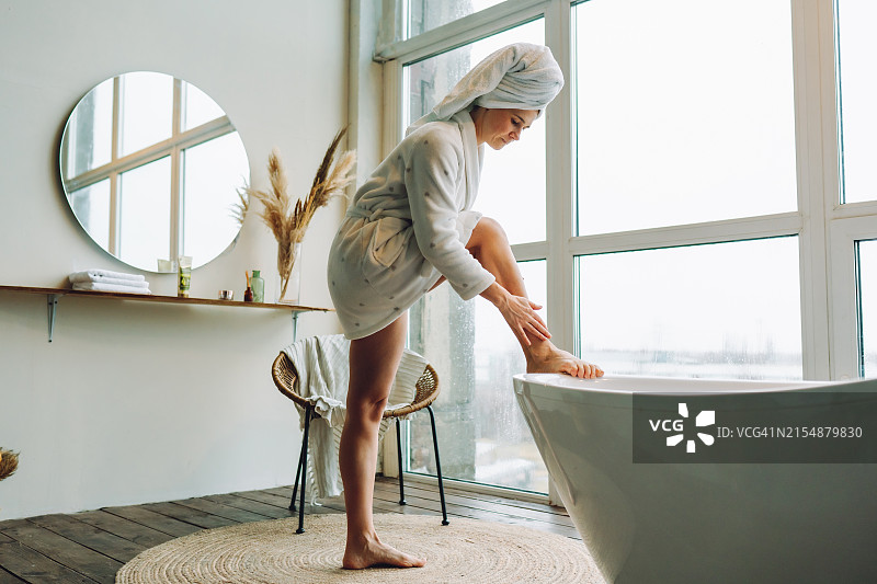 浴室中的腿部护理和淋巴引流，沐浴后，女人滋润她光滑的腿图片素材