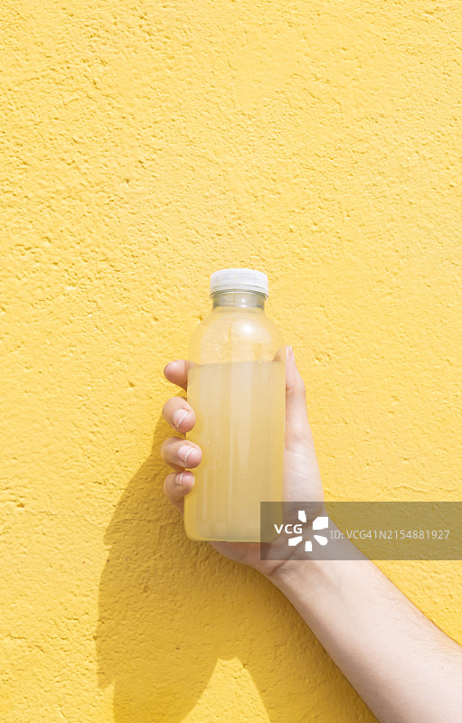 女人手拿一瓶果汁，黄色背景图片素材