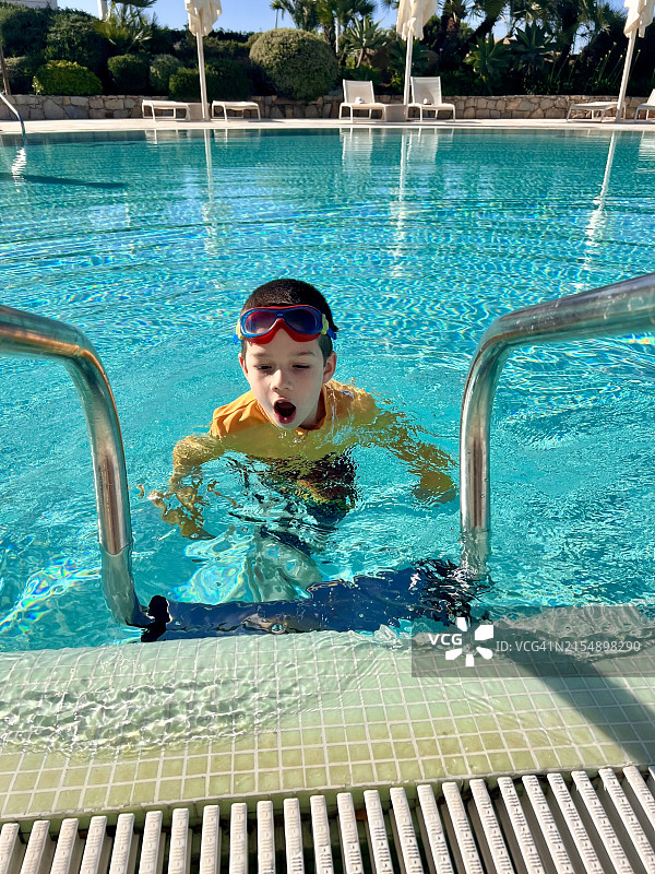 男孩从游泳池里爬出来特写图片素材