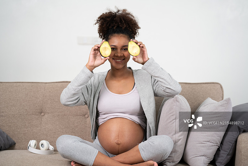 孕妇微笑展示手中切好的牛油果片图片素材