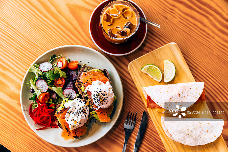 牛油果吐司配三文鱼、水波蛋、沙拉、墨西哥卷饼和冰咖啡图片素材