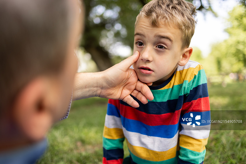 过敏季，叔叔用手指擦去堂弟的眼泪图片素材
