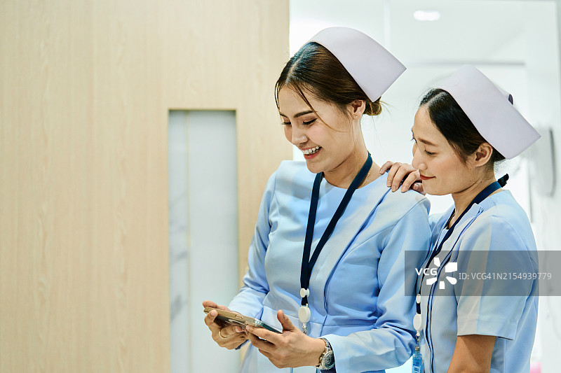 休息期间使用手机的快乐年轻女护士图片素材