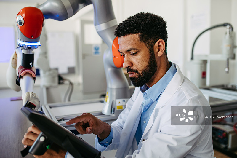 机器人工程师正在研究机器人膝关节置换手术项目，手持平板电脑，仔细观察。医疗保健中机器人技术、工程和计算机科学的概念。图片素材